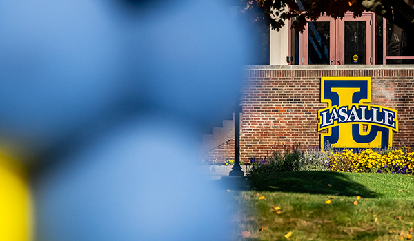 Image of blue and yellow out-of-focus balloons in front of the La Salle "L."