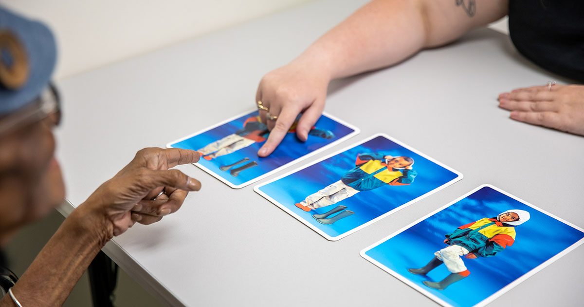 people pointing to cards on a table