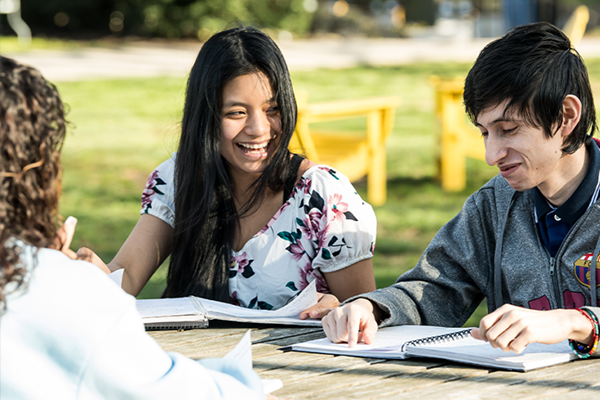 Image of students sitting at a table and laughing on the Hansen Quad.
