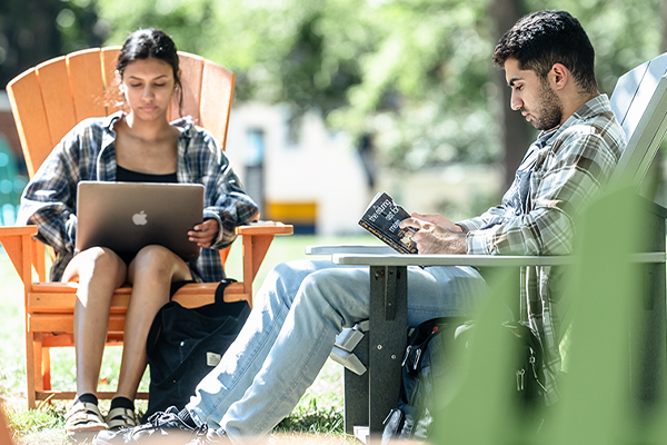 Image of two students working on laptops in the Hansen Quad.