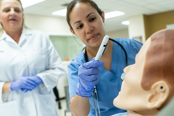 Image of a professor and student working in the nursing simulation labs.