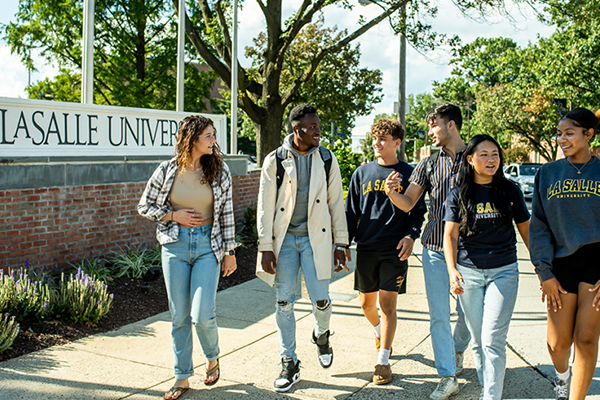 A group of students walking in front of the La Salle University sign. 