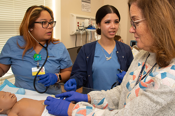 Students and a professor working in the nursing simulation labs.