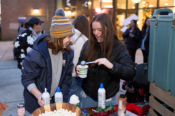 Two female students getting hot chocolate at the Holiday Village.
