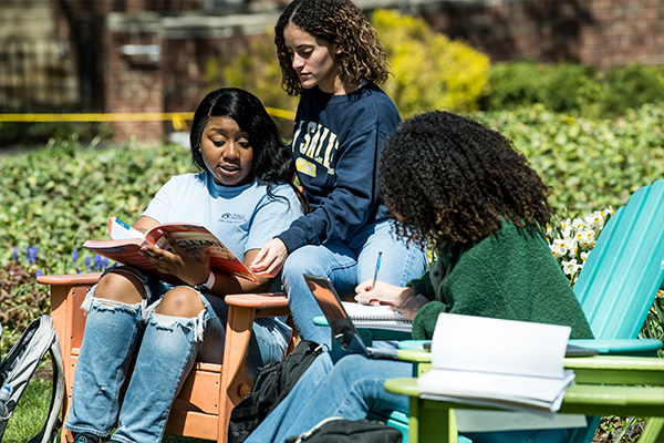 Image of three students sitting outside on the Hansen Quad.