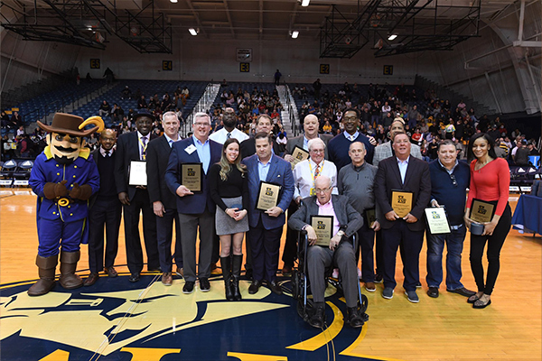Image of the Hall of Athletes inductees posing for a photo at a basketball game.