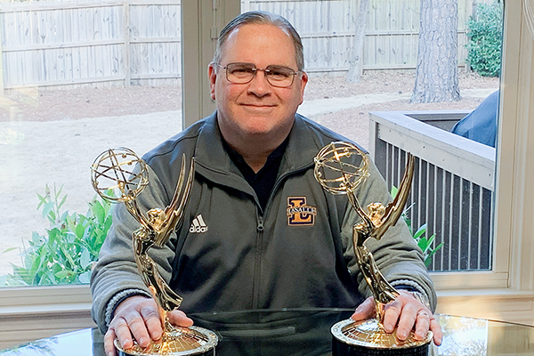 Albert “Scooter” Vertino, ’93, poses with his most recent Emmy Award statuettes in his home in Georgia.