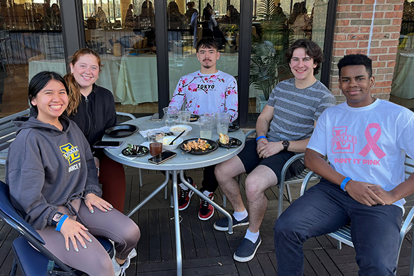 Image of five students eating outside at Community Dinner.