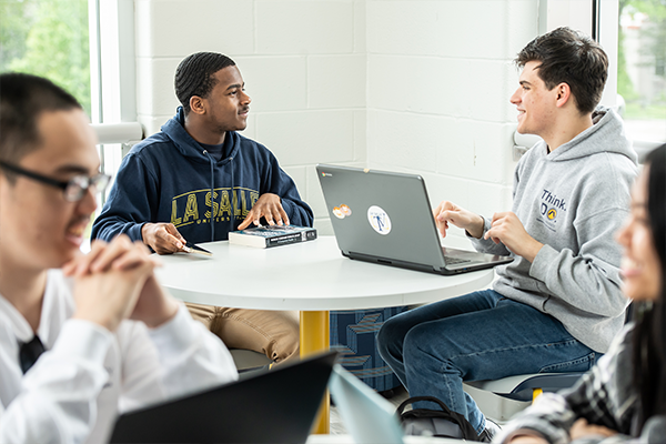 Image of two male students talking at a table.