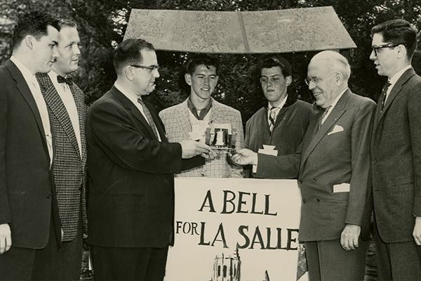 An archival image of La Salle receiving a bell. 