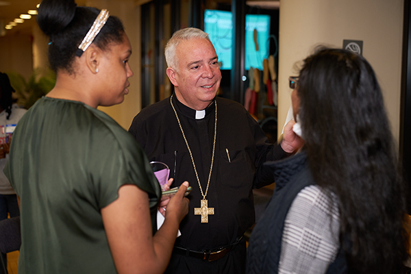 The Most Reverend Nelson J. Perez speaking with two students.
