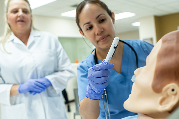 A student and professor working in the nursing simulation labs.