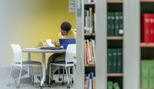 Image of a male student working in the library.