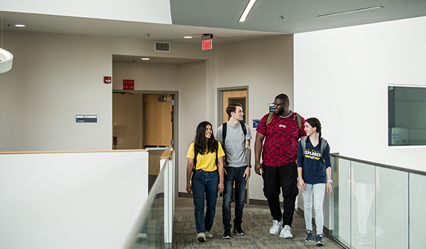 Image of four students walking down a hallway.