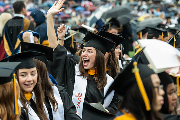 Image of students waving and smiling during the Commencement Ceremony.