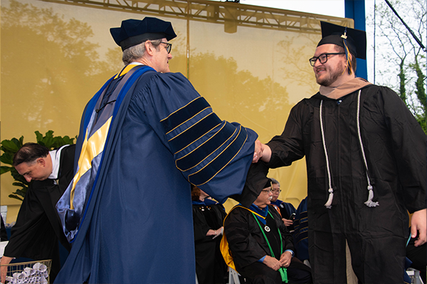 A student shaking President Allen's hand at Commencement.
