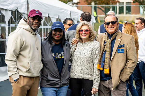 Image of four alumni smiling at Homecoming.