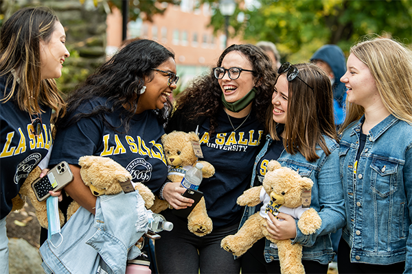 A group of La Salle students laughing and holding plush bears.