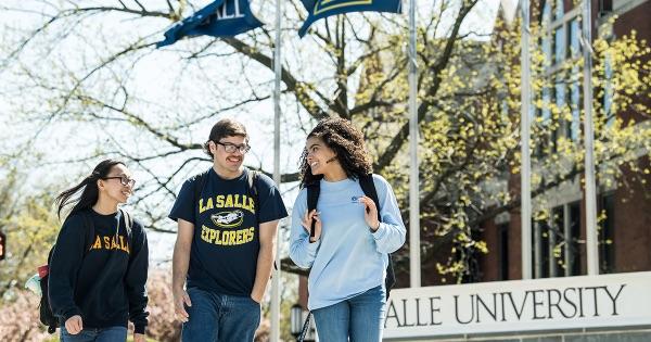 Students walking together past the monument sign